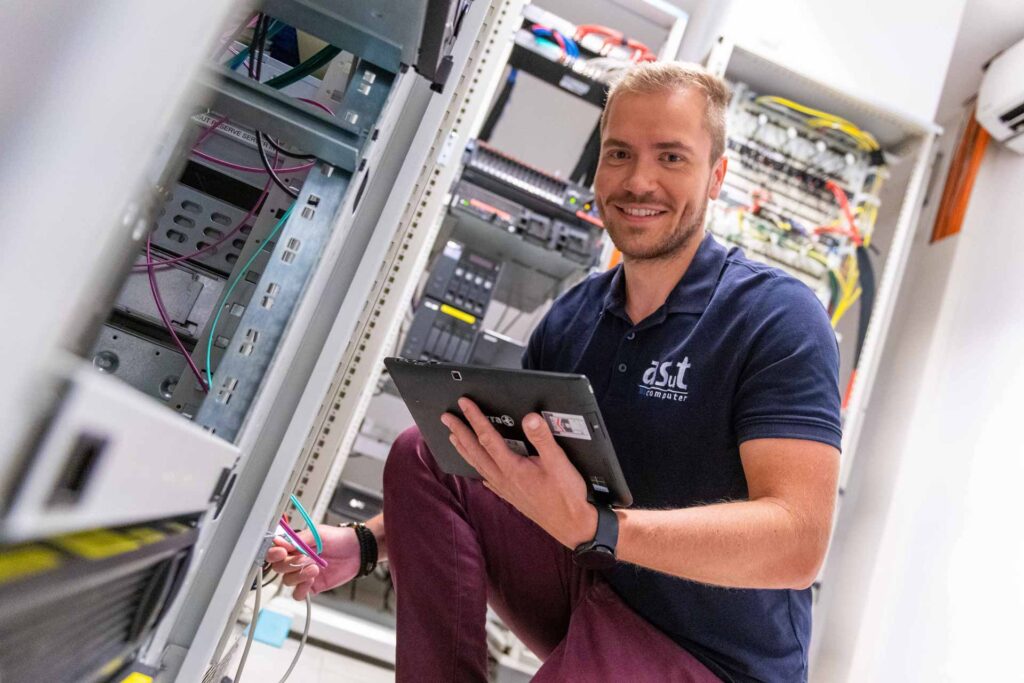IT-Techniker von asut computer bei der Arbeit im Serverraum – Netzwerkverkabelung und Systemwartung mit Tablet