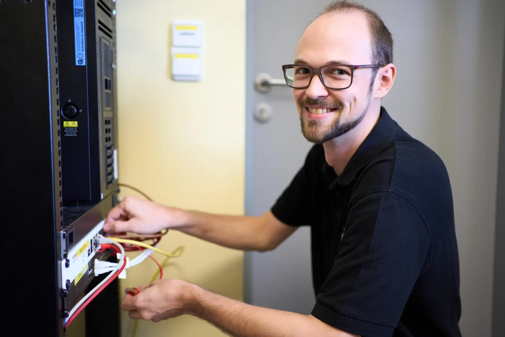 IT-Techniker von asut computer arbeitet an einem Serverrack und verbindet Netzwerkkomponenten für eine stabile IT-Infrastruktur.
